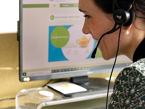 FRÖBEL Recruiting Day: Eine Frau mit Headset sitzt vor einem Rechner